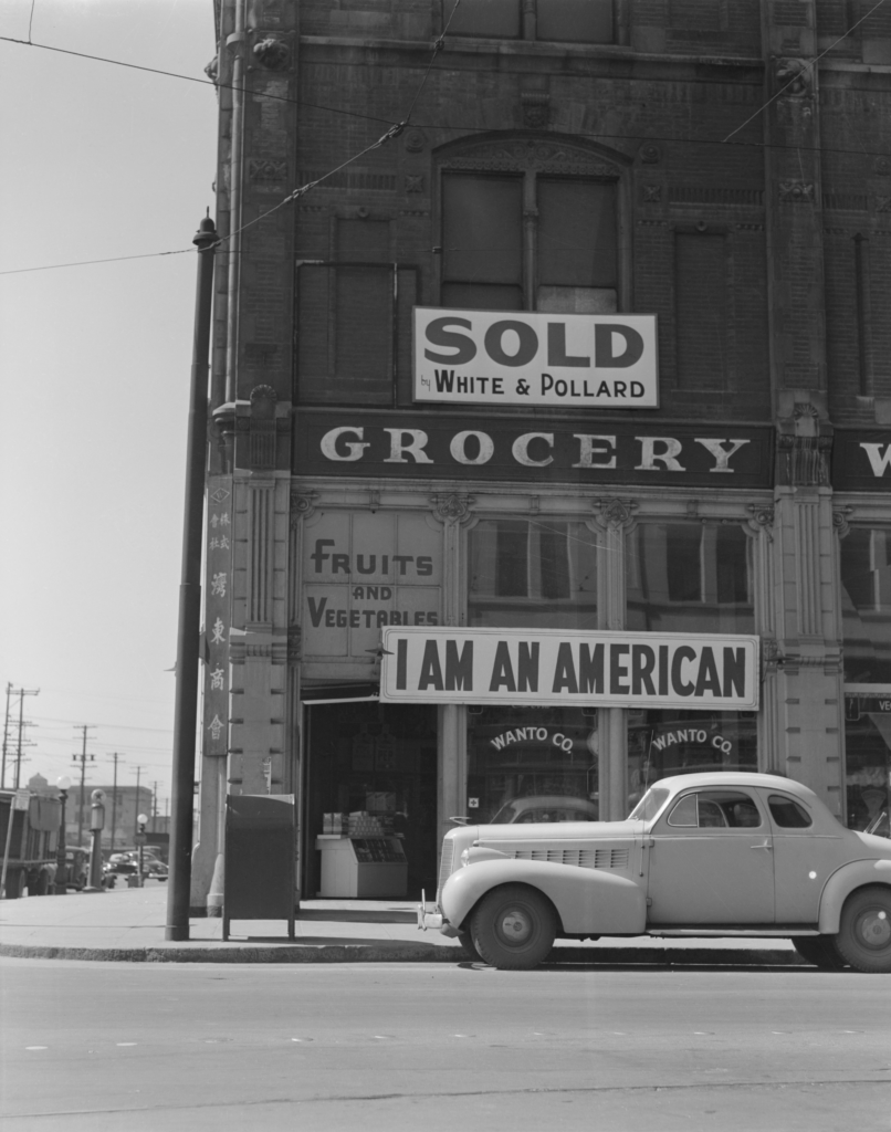 Agfa Safety Film negative Dorothea Lange's WRA caption for photographs in this series reads: "Oakland, Calif., Mar. 1942. A large sign reading "I am an American" placed in the window of a store, at [401 - 403 Eighth] and Franklin streets, on December 8, the day after Pearl Harbor. The store was closed following orders to persons of Japanese descent to evacuate from certain West Coast areas. The owner, a University of California graduate, will be housed with hundreds of evacuees in War Relocation Authority centers for the duration of the war