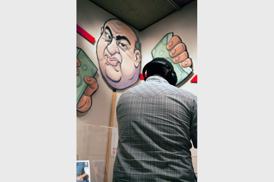 Un visitante en una de las estaciones de escucha frente a la marioneta del ex canciller de la CSU Charles Reed. Museo de Oakland de California, 2013. Foto: Ryan LeBlanc.