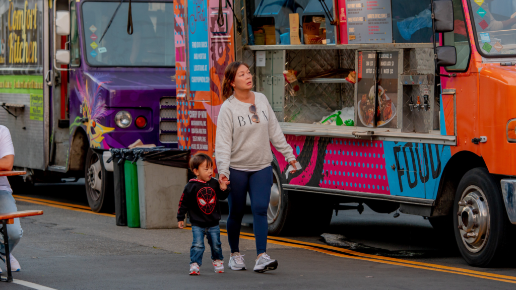 Woman and child walking in front of food truck at OMCA