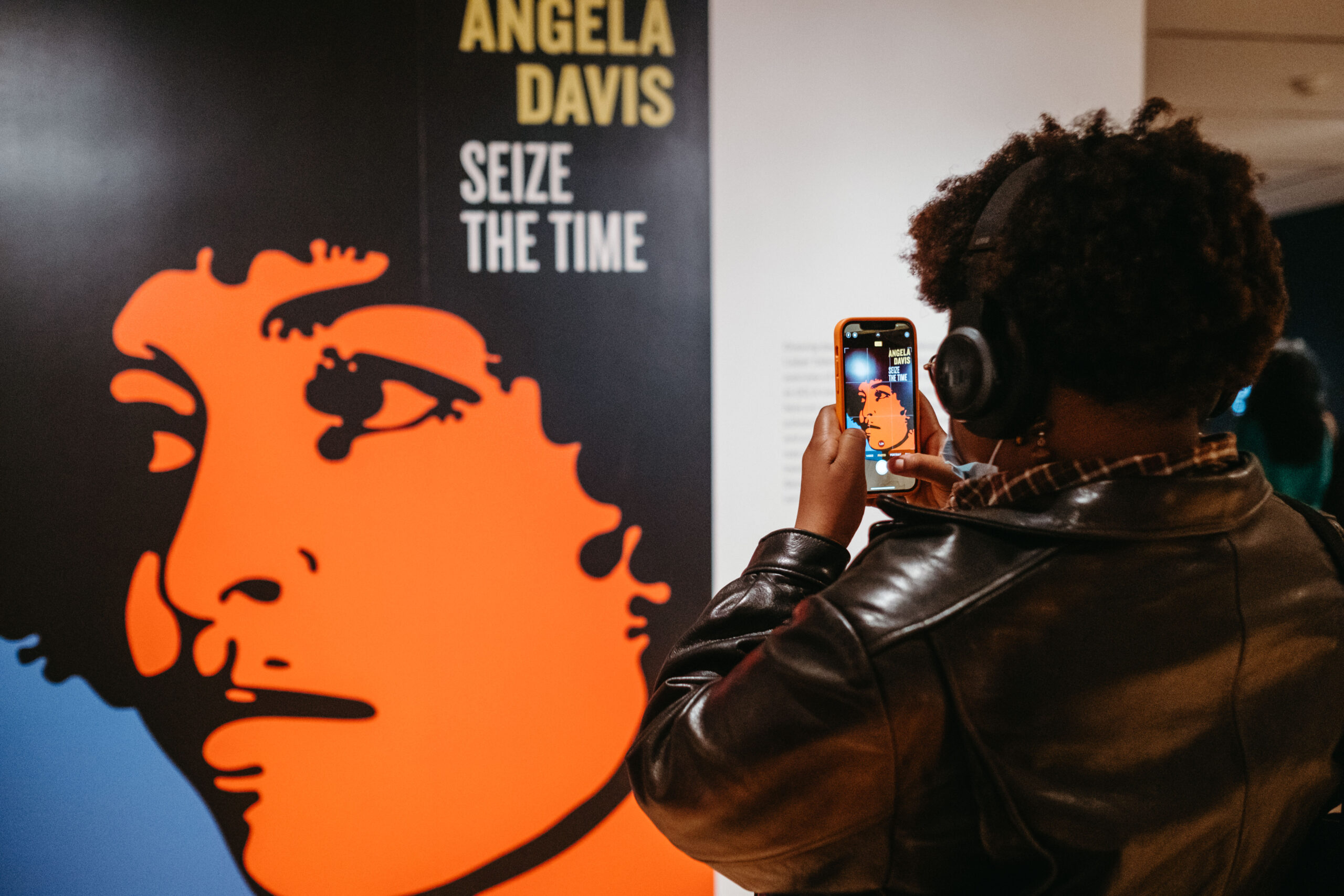 A woman taking a picture of a picture of Angela Davis at OMCA