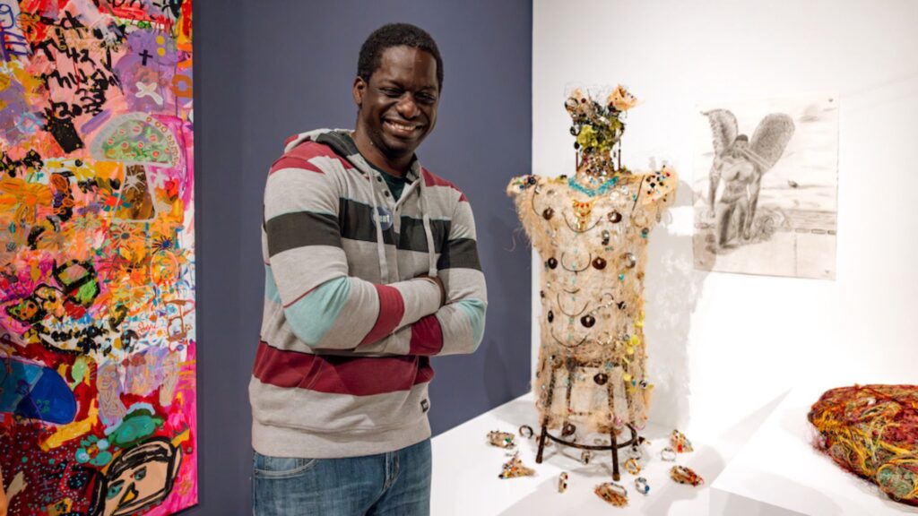 Un artista junto a su escultura en OMCA