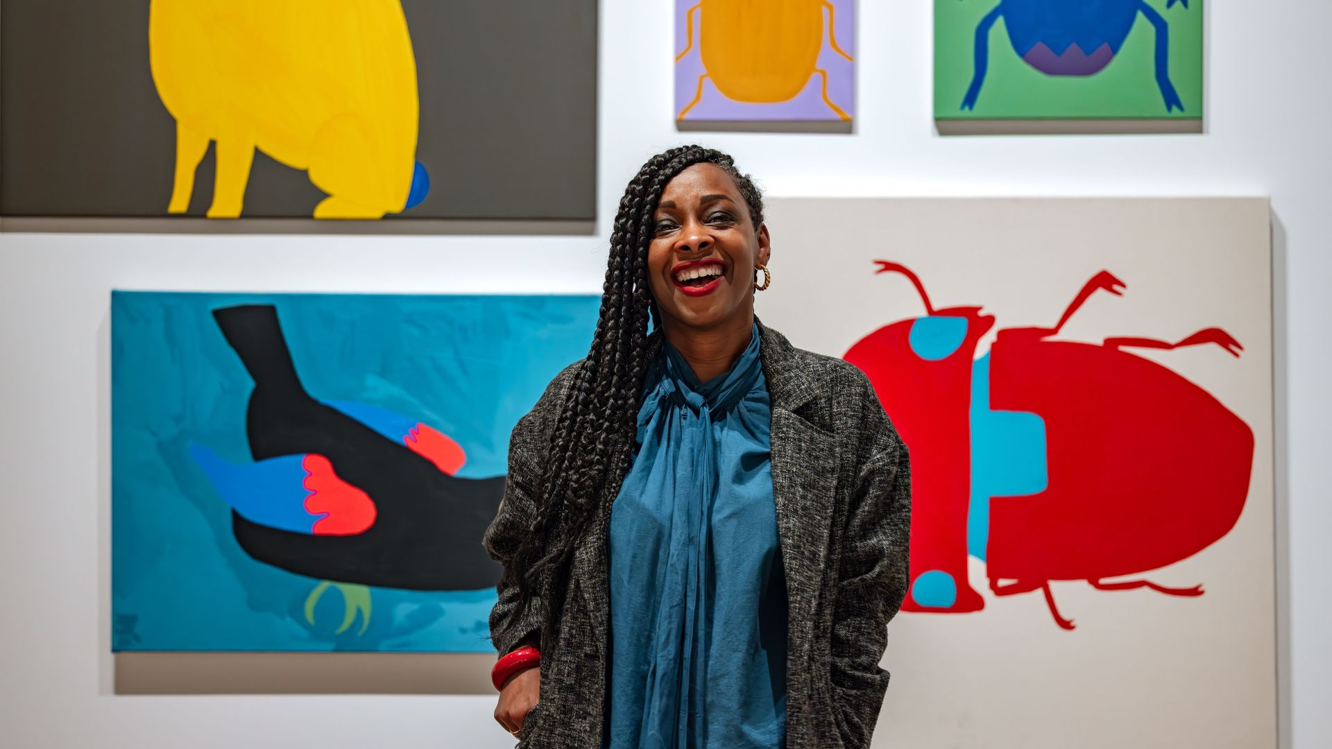 Woman standing in front of colorful paintings at OMCA